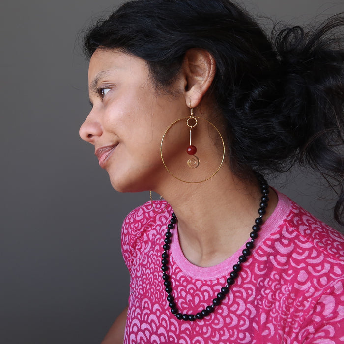 female wearing carnelian hoop earrings