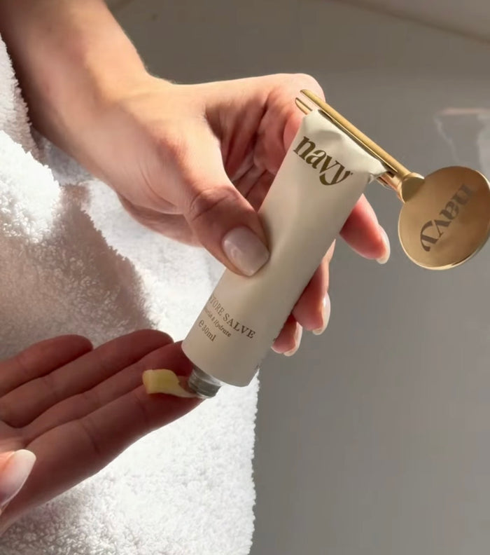 Hand applying a cream from a 'navy' branded tube onto another hand.