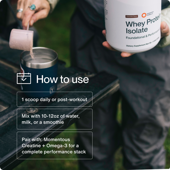 Person scooping chocolate-flavored whey protein isolate powder into a metal cup outdoors.