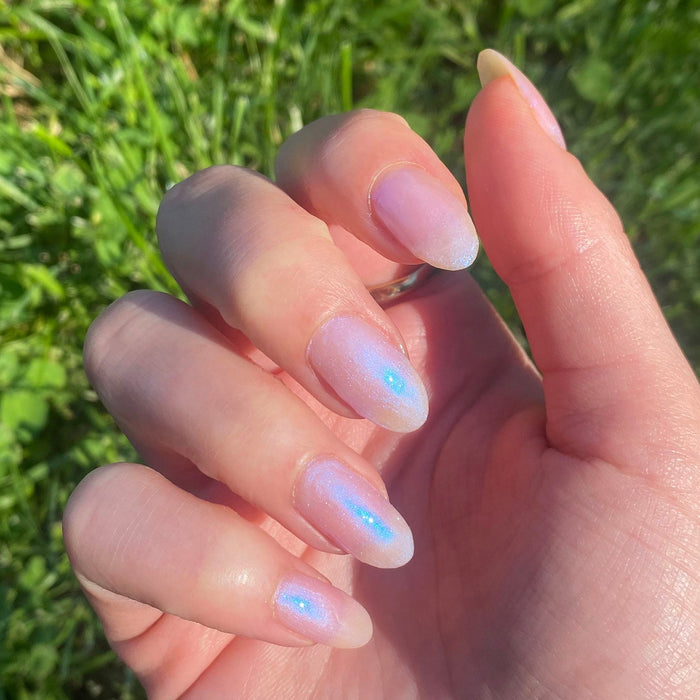 Fingernails with Pink Goldfish sheer iridescent polish showing a soft, luminous manicure in natural light outdoors