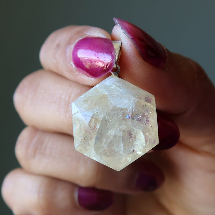 Faceted Citrine crystal held between fingers with a blurred background