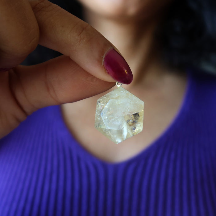Person holding a Citrine crystal pendant with a blurred background