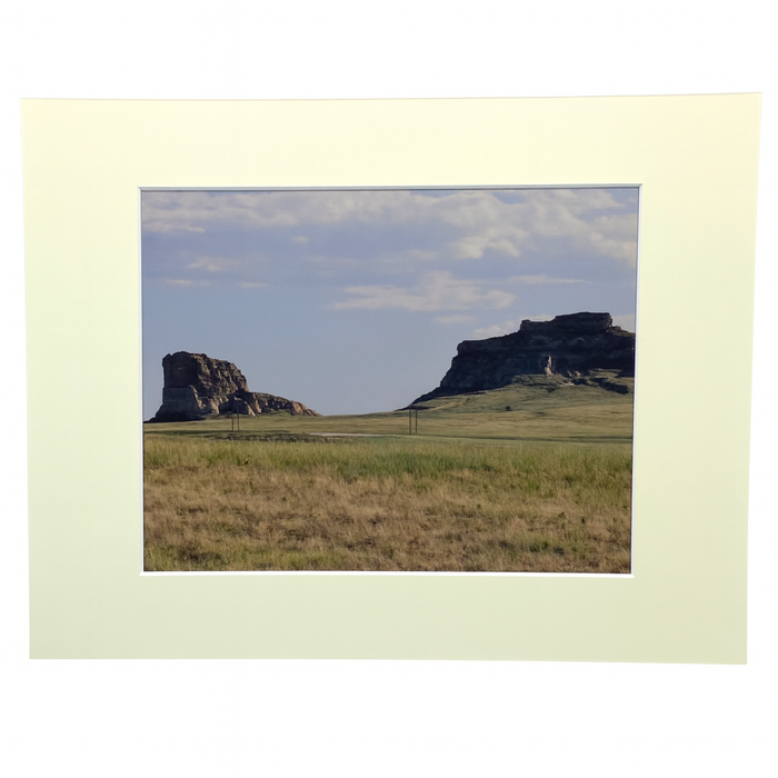 Scenic landscape with rocky outcrops and grasslands framed by a light border