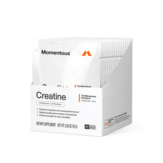 A white box containing 15 individual Momentous Creatine Monohydrate single-serve powder packets, Unflavored. The front of the box displays the Momentous logo and orange mountain icon, an "Unflavored | 15 Packets" badge, and an orange "The Momentous Standard Signature Spec" label. Three bullet points list product benefits: supports cognitive and muscle performance, highest quality pure creatine monohydrate, and ultrafine powder for easy mixability. Net weight is 2.65 oz (75g).