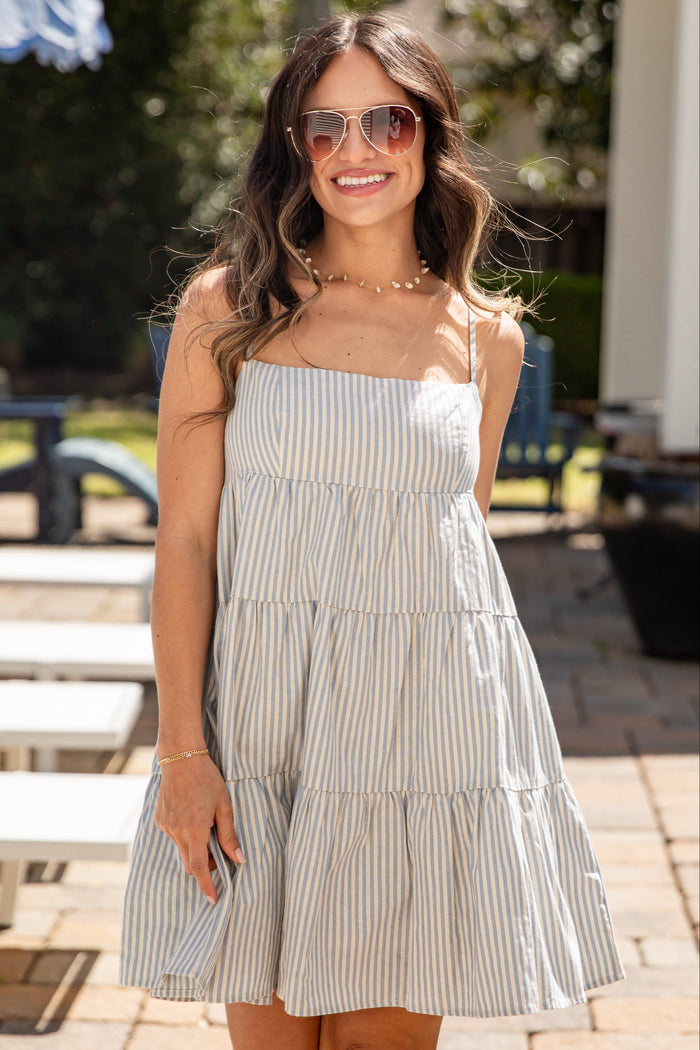 Woman wearing a striped dress standing outdoors on a sunny day.