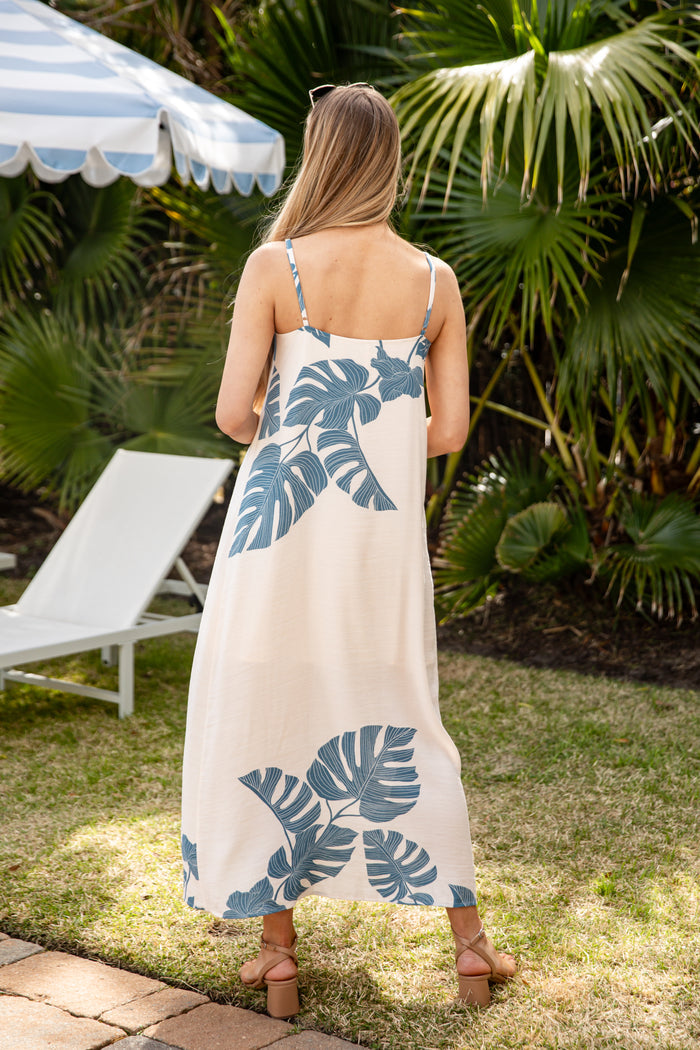 Woman wearing a long dress with blue leaf patterns in a garden setting