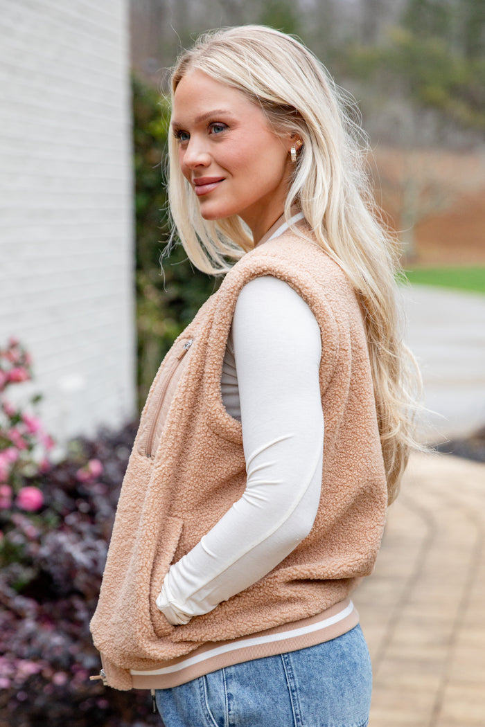 Woman wearing a beige fleece vest outdoors with blurred background