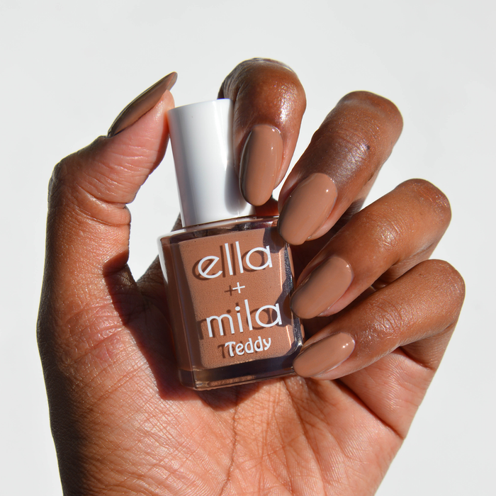 Honey Bear neutral cool brown nail polish on a deep skin tone, hand holding the bottle