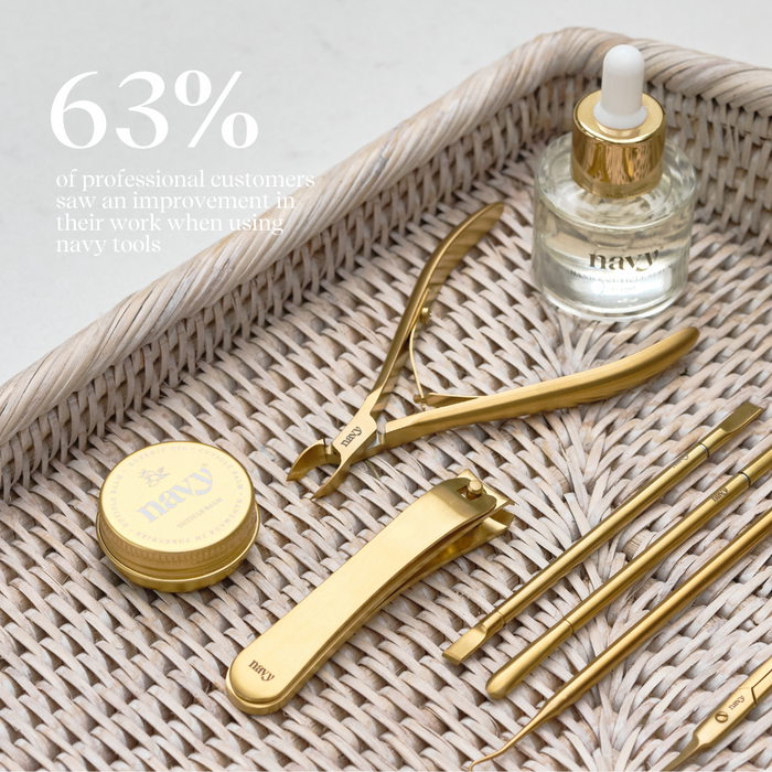 Set of gold facial tools on a woven tray with a dropper bottle labeled 'navy'.