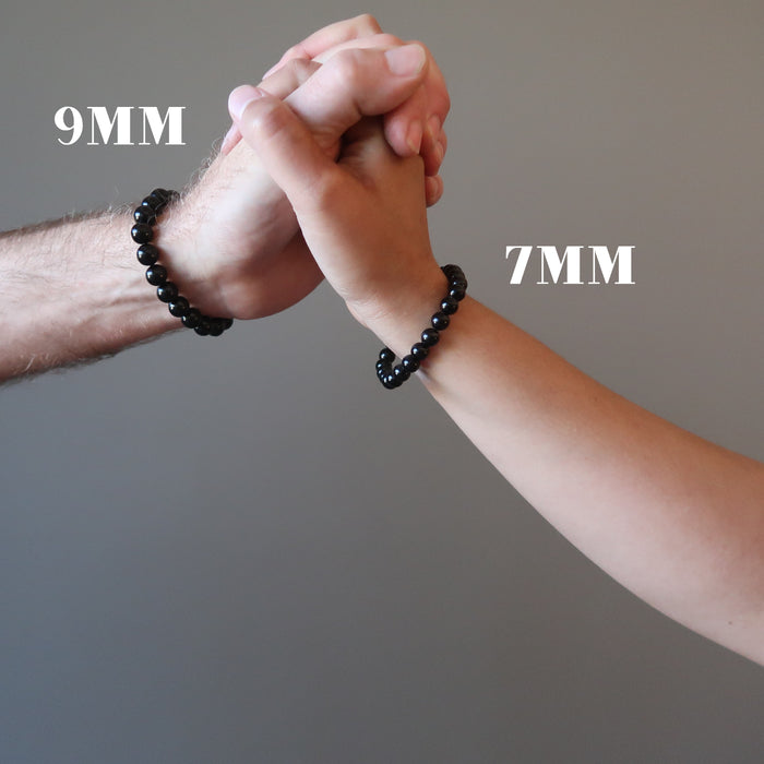 man and woman's hands clasped wearing black jet stone round beaded stretch bracelets