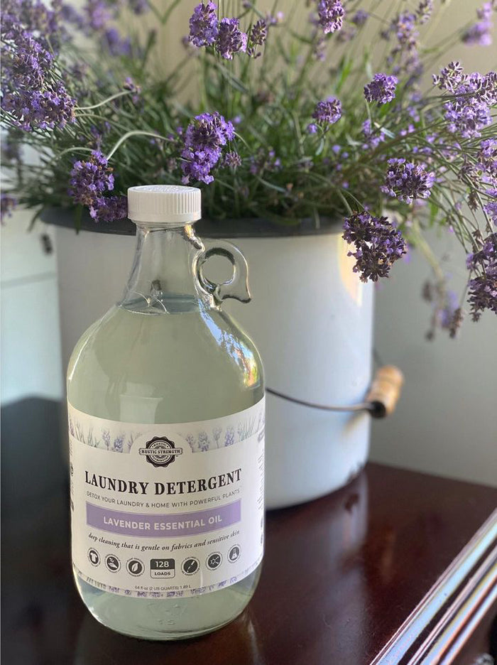 Rustic Strength - Laundry Detergent | 64oz Glass in front of a bunch of lavender