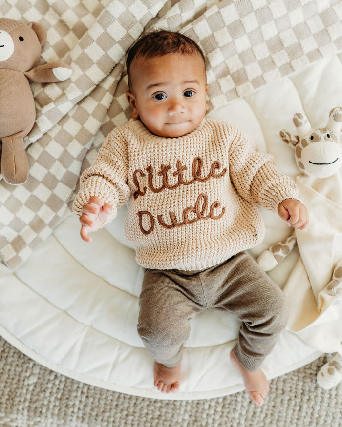 Baby wearing Viverano organic cotton beige knitted top with little dude text