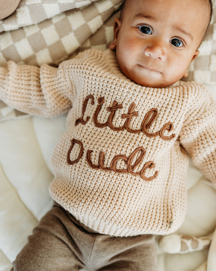 Baby wearing Viverano Organics beige knitted top with Little Dude text in organic cotton