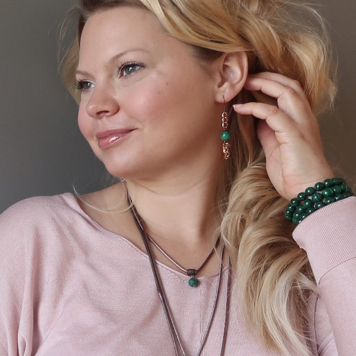 woman wearing malachite copper chain earrings and malachite bracelets
