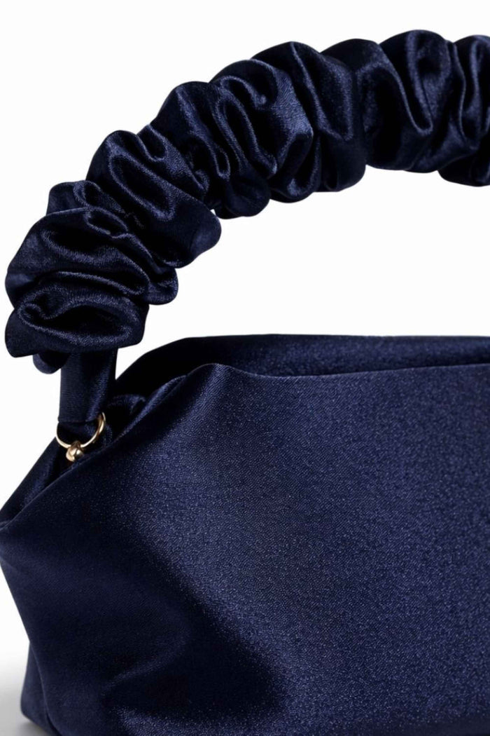 Close-up of navy satin scrunch handle on the clutch bag, showcasing the shiny, gathered fabric and elegant design.