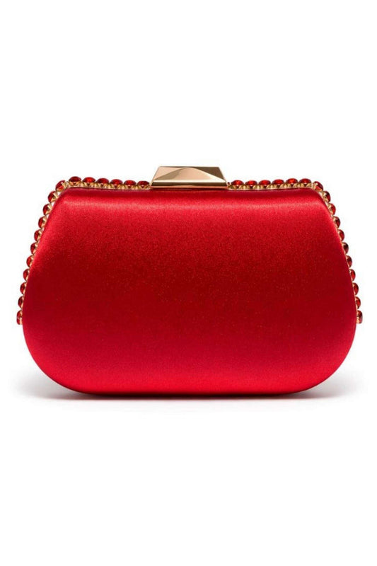 Close-up of a red satin clutch with a structured rounded shape, embellished with a gold-tone border of red gemstones, featuring a gold clasp on top.