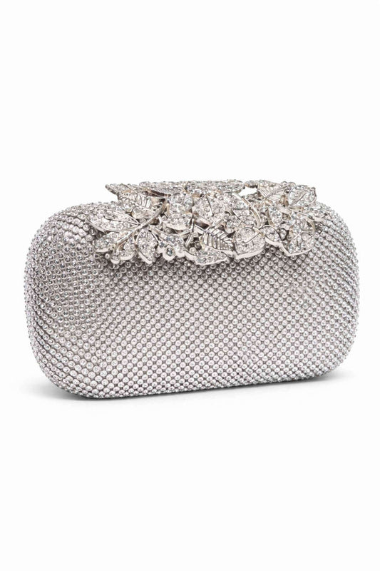 Silver clutch bag covered in small beads with a decorative silver-tone floral and leaf clip adorned with sparkling rhinestones, perfect for evening events.