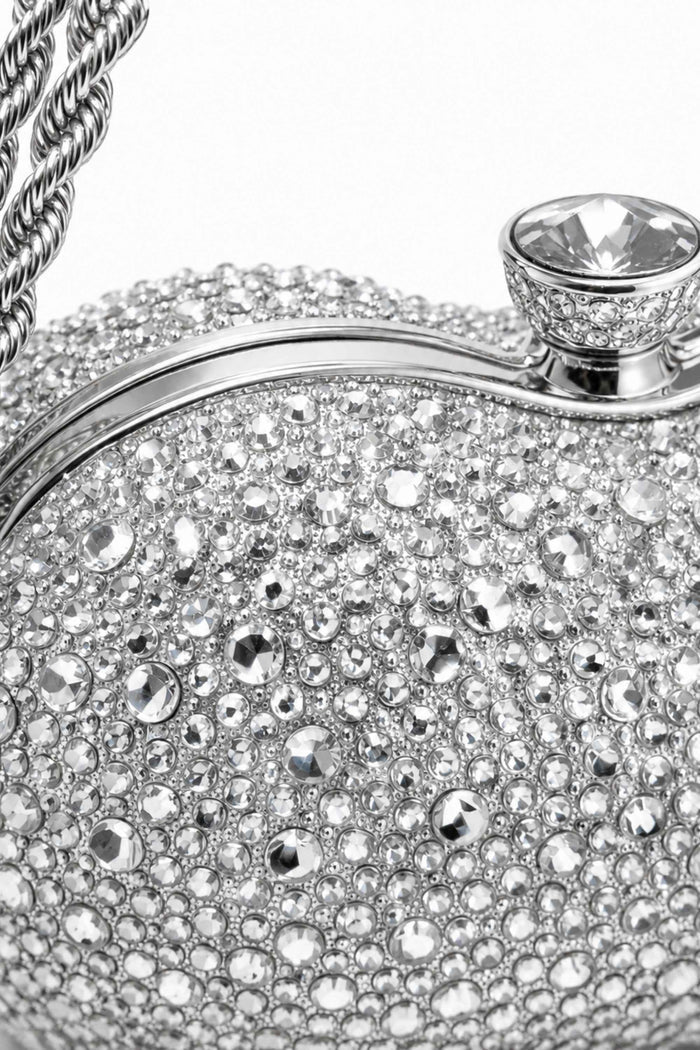 Detailed view of rhinestone-studded silver clutch with a prominent gemstone clasp and twisted chain handle, glamorous accessory for special occasions