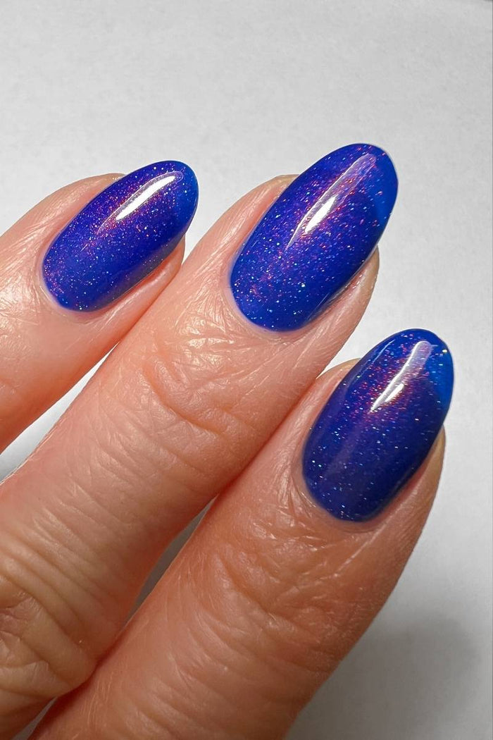 cobalt blue shimmer nail polish on hand model close up