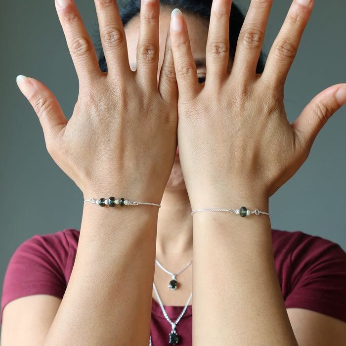 woman wearing two moldavite bracelets