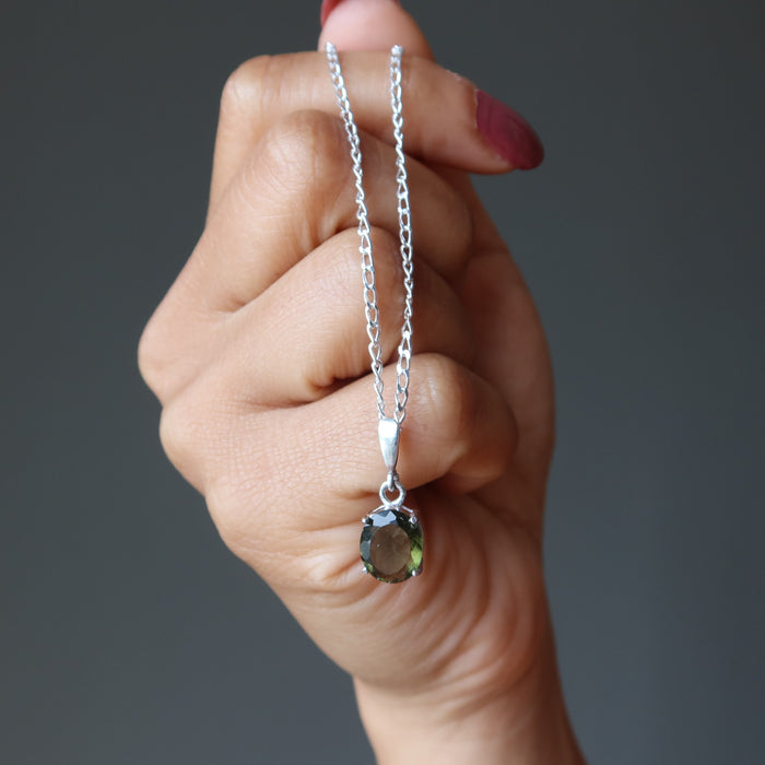 hand holding faceted moldavite pendant necklace