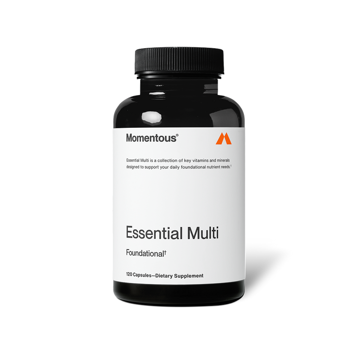 Black bottle of Momentous Essential Multi capsules centered on a transparent background. Text on the label reads: “Momentous®” “Essential Multi is a collection of key vitamins and minerals designed to support your daily foundational nutrient needs.*” “Essential Multi” “Foundational†” “120 Capsules—Dietary Supplement”