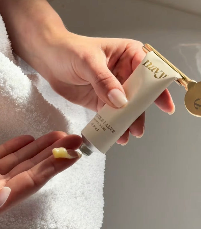 Hand holding a tube of 'Navy' cream with a blurred background