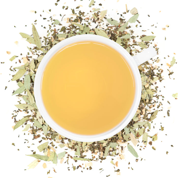 A white cup of Organic Constipation Relief tea surrounded by the loose leaf blend.