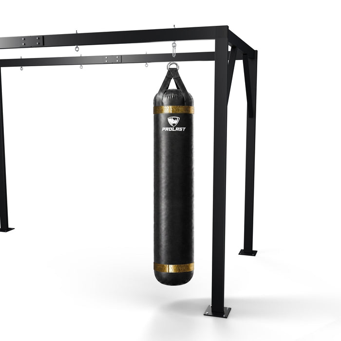 PROLAST 6 ft 150 lb stock heavy bag, black with gold trims, hanging from a PROLAST heavy bag frame on a steel snap hook through its D-rings (stand sold separately)