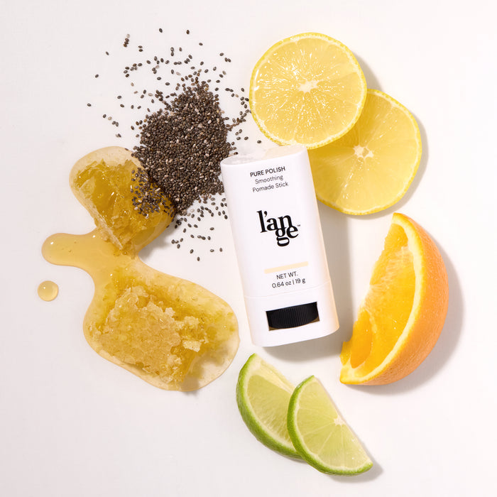 L’ange Pure Polish Smoothing Pomade  Stick surrounded by citrus slices, honey, and chia seeds.