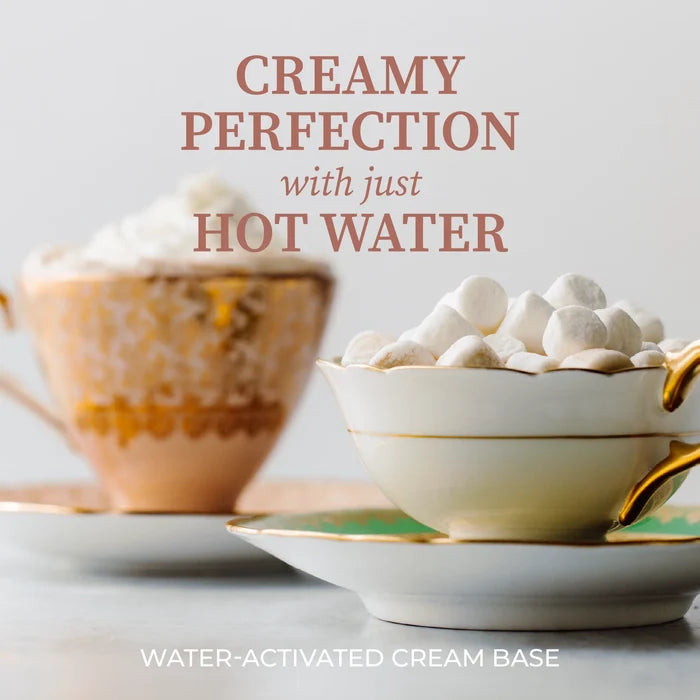 A styled product graphic showing two teacups on saucers with marshmallows and whipped cream, overlaid with the text 'CREAMY PERFECTION with just HOT WATER' and 'WATER-ACTIVATED CREAM BASE' on a light neutral background.