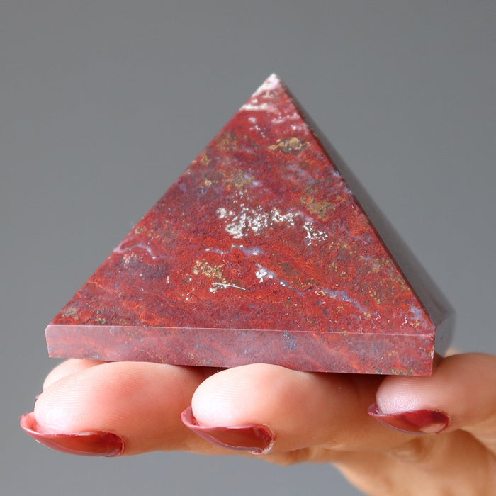 hand holding red jasper pyramid