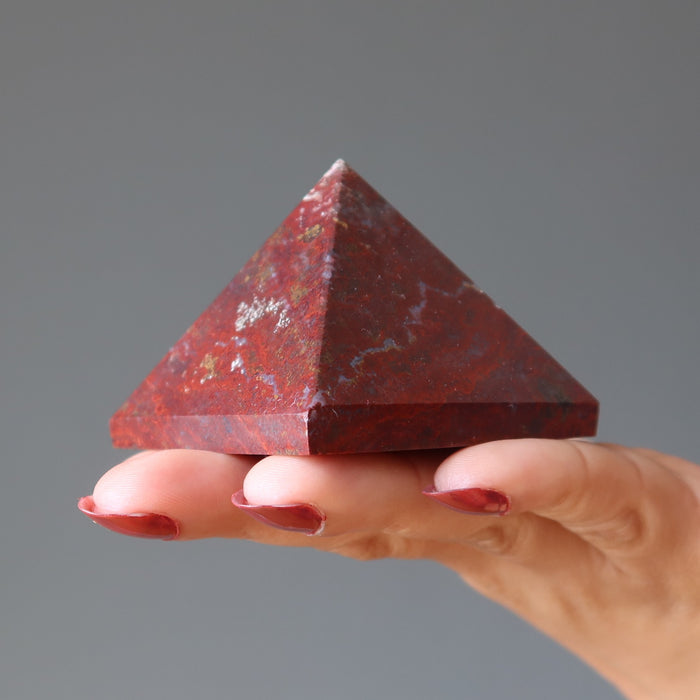 hand holding red jasper pyramid