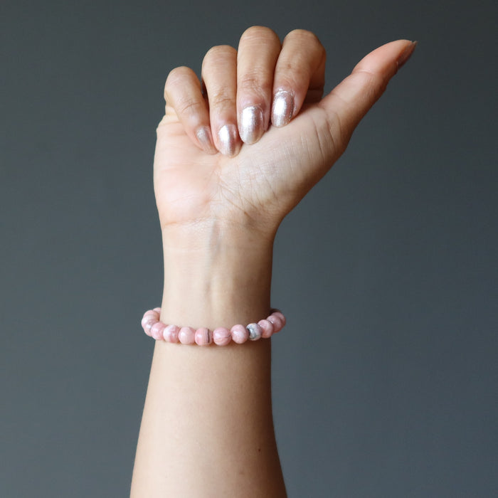 hand wearing rhodochrosite round beaded stretch bracelet