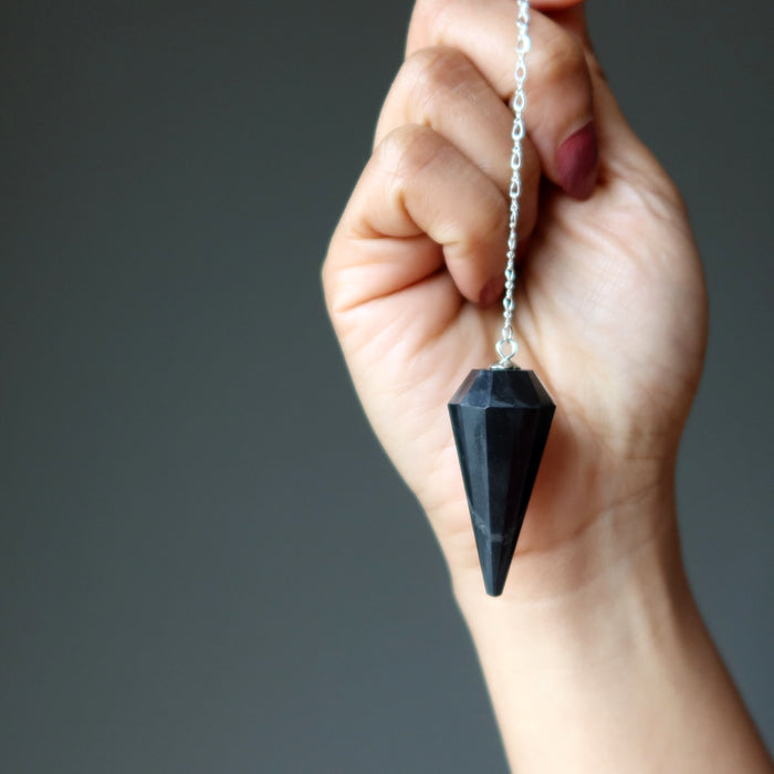 hand holding shungite pendulum