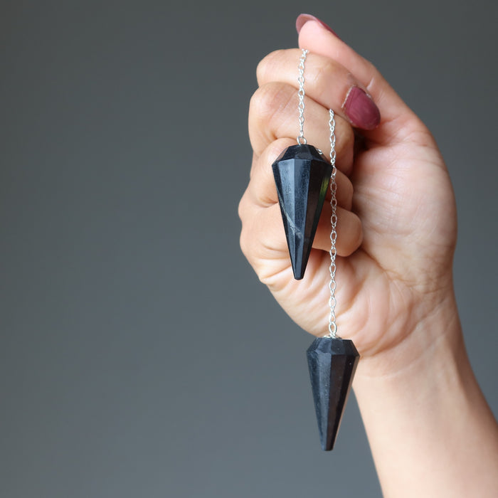 hand holding shungite pendulums