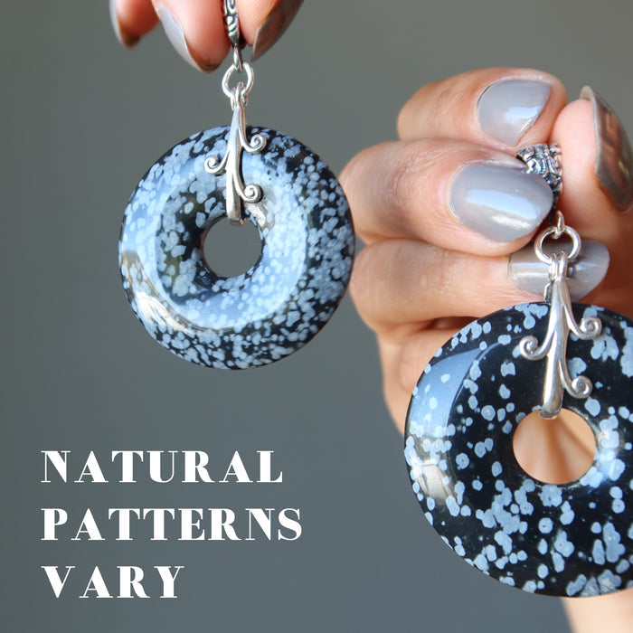 hand holding snowflake obsidian donut pendants