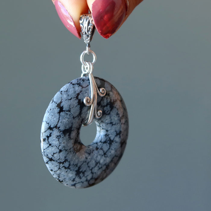 hand holding snowflake obsidian donut pendant