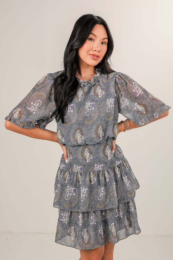 Woman wearing a gray patterned dress against a plain background