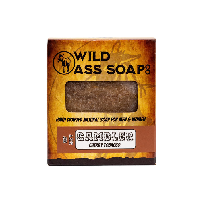 A packaged bar of soap labeled 'Gambler Cherry Tobacco' from Wild Ass Soap Co with a brown and beige color scheme.