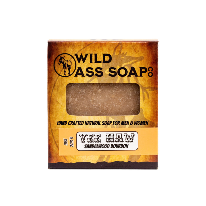A bar of soap with a brownish tint, packaged in a rectangular box with a logo and the text 'WILD ASS SOAP’S YEE HAW Sandalwood Bourbon'.