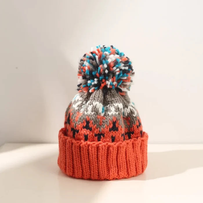 Cozy knit snowflake beanie with fluffy pom-pom shown in multiple colors