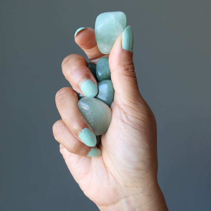 hand holding green aventurine tumbled stones