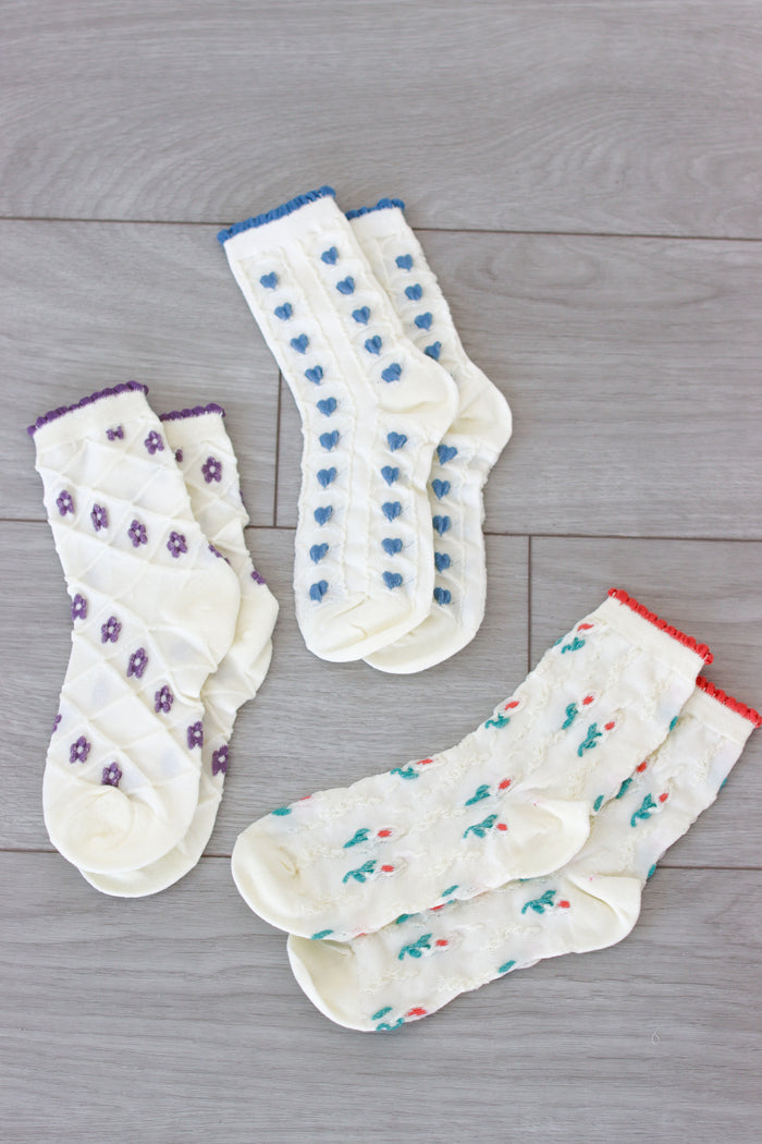 3 pairs of socks in purple, blue and red displayed on the floor
