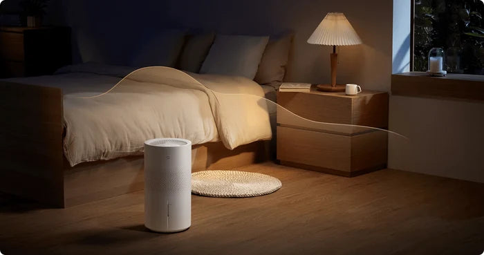 Xiaomi Smart Evaporative Humidifier Pro naast het bed in een slaapkamer bij avondlicht